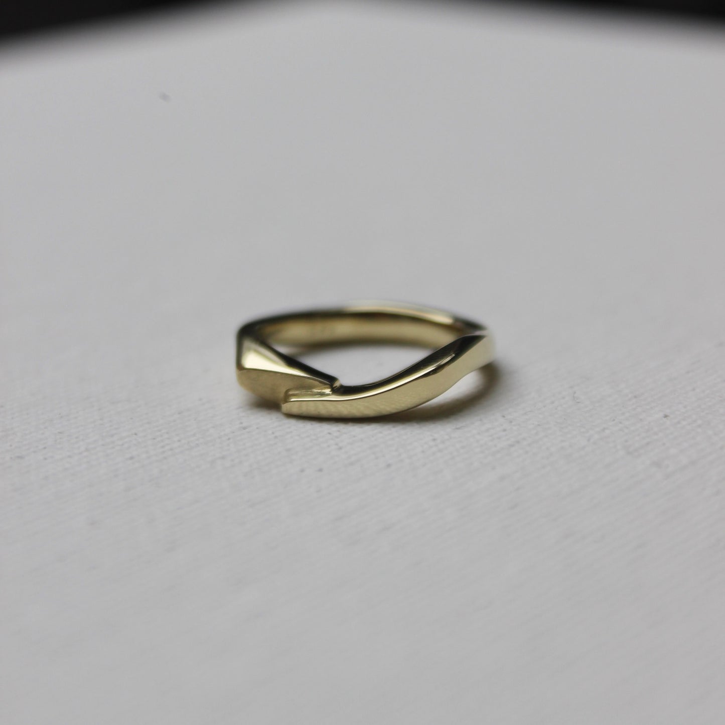 Gold ring with an organic shape on a light gray background