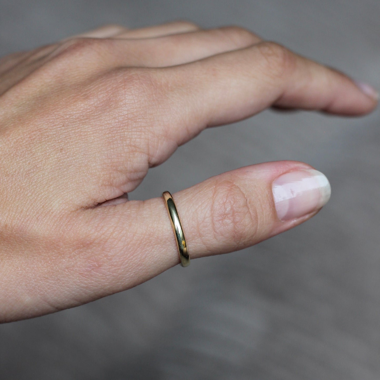 Hand wearing a gold ring on a blurred background