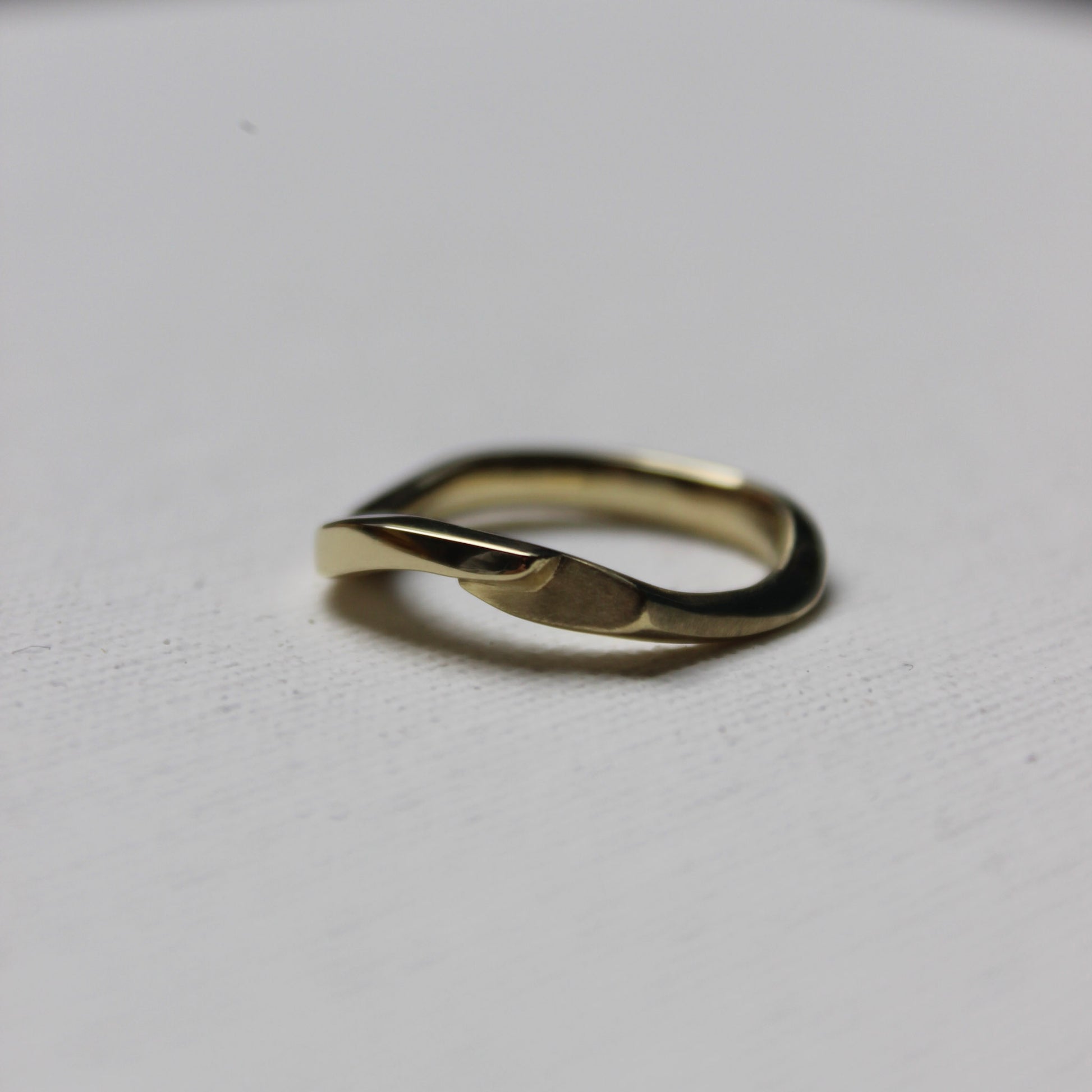 Gold ring with a unique design on a light gray background