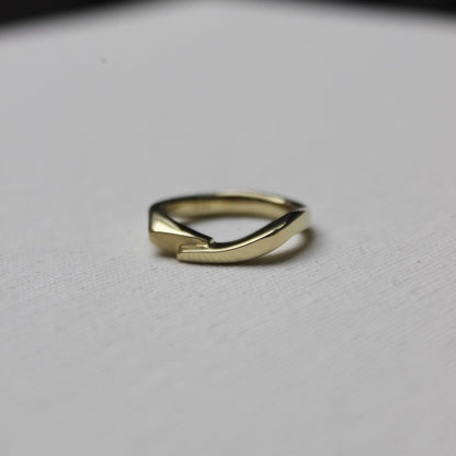 Gold ring with an organic shape on a light gray background