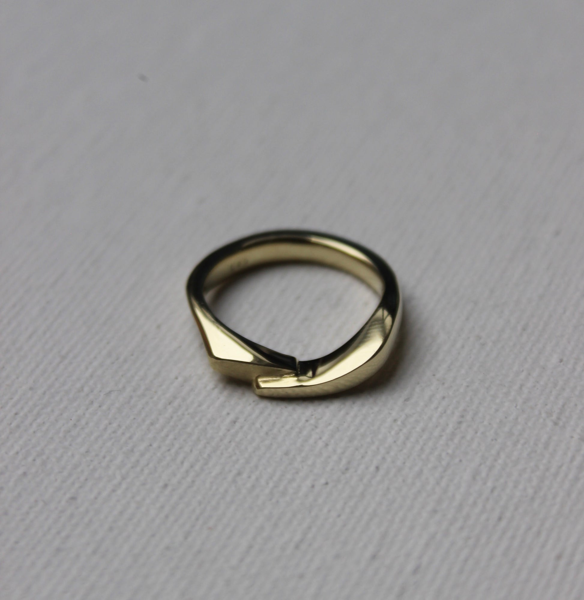 Gold ring with a unique design on a gray background