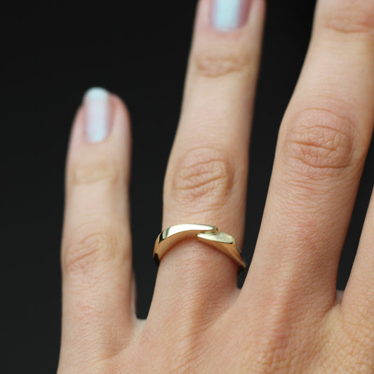 Gold ring on a finger against a black background